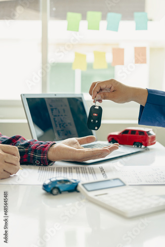 Car rental service concept Close up view of hands of representative handing car keys to customer after signing lease contract, document contract, vehicle. Sales agreement vertical picture