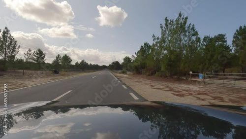 First person view, FPV, from dashcam of car driving along the Alentejo Coast in Portugal, passing cork oak trees and sand dunes. Road trip video in POV photo