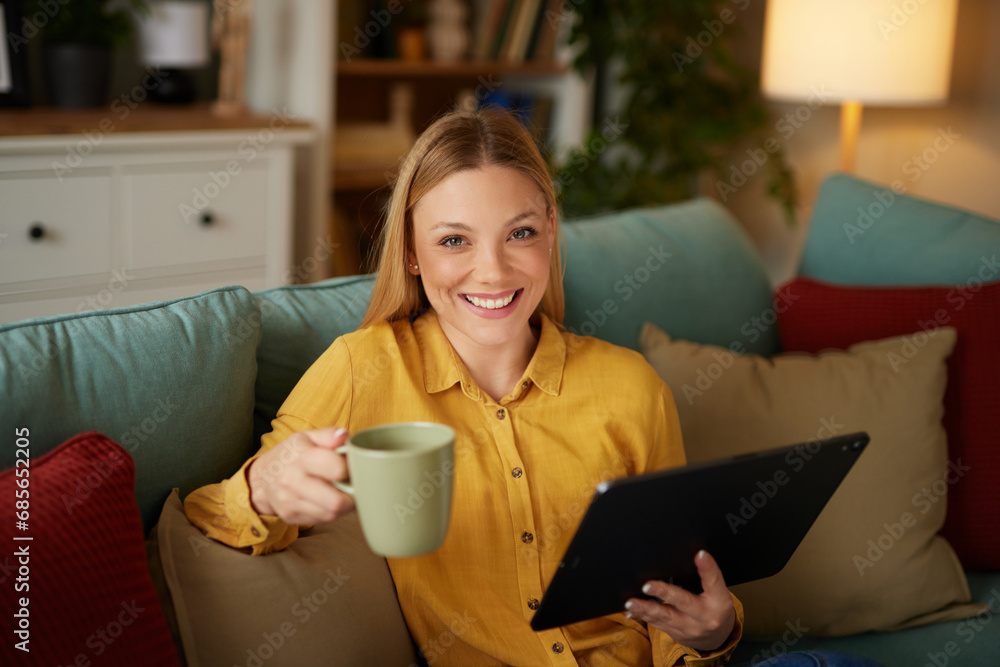 A pretty woman using a digital tablet while enjoying a cup of coffee at home A pretty woman using a digital tablet while enjoying a cup of coffee at home