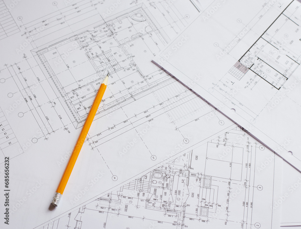 pencil and office tools for writing on the blueprint of construction industry. Place the rolls on a desk over blurred blueprint for construction industry background. pencil and office tools for writing on the blueprint of construction industry. Place the rolls on a desk over blurred blueprint for construction industry background.