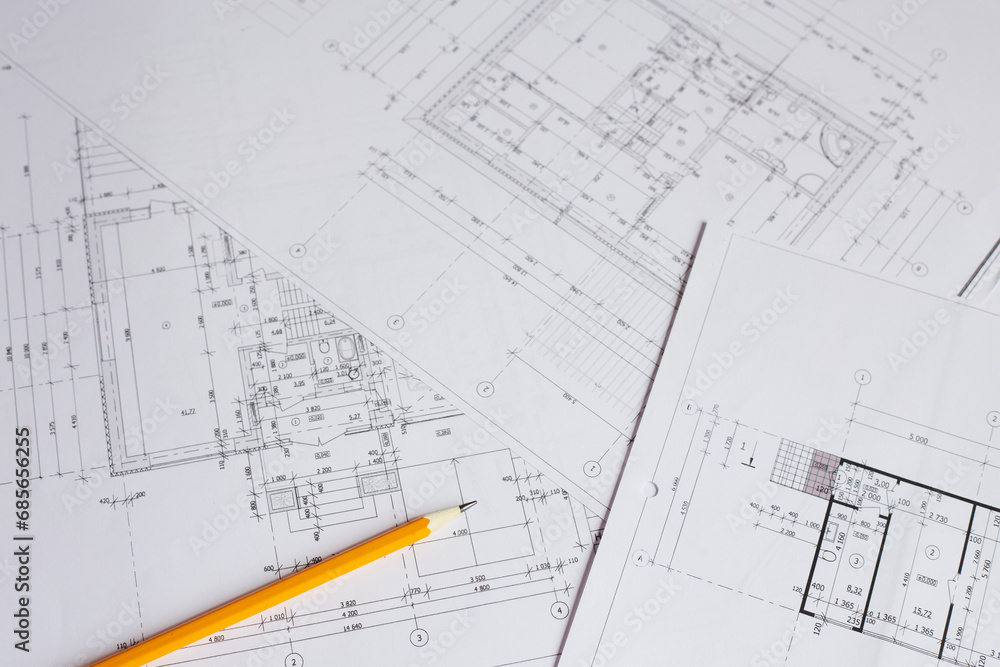 pencil and office tools for writing on the blueprint of construction industry. Place the rolls on a desk over blurred blueprint for construction industry background. pencil and office tools for writing on the blueprint of construction industry. Place the rolls on a desk over blurred blueprint for construction industry background.