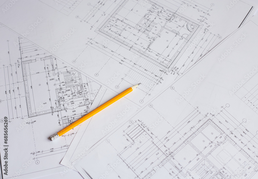 pencil and office tools for writing on the blueprint of construction industry. Place the rolls on a desk over blurred blueprint for construction industry background. pencil and office tools for writing on the blueprint of construction industry. Place the rolls on a desk over blurred blueprint for construction industry background.