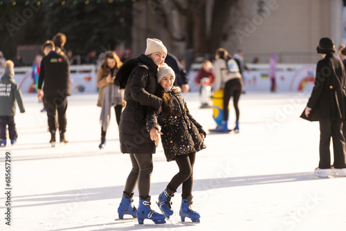 Adorable young mother with her daughter on the ice rink