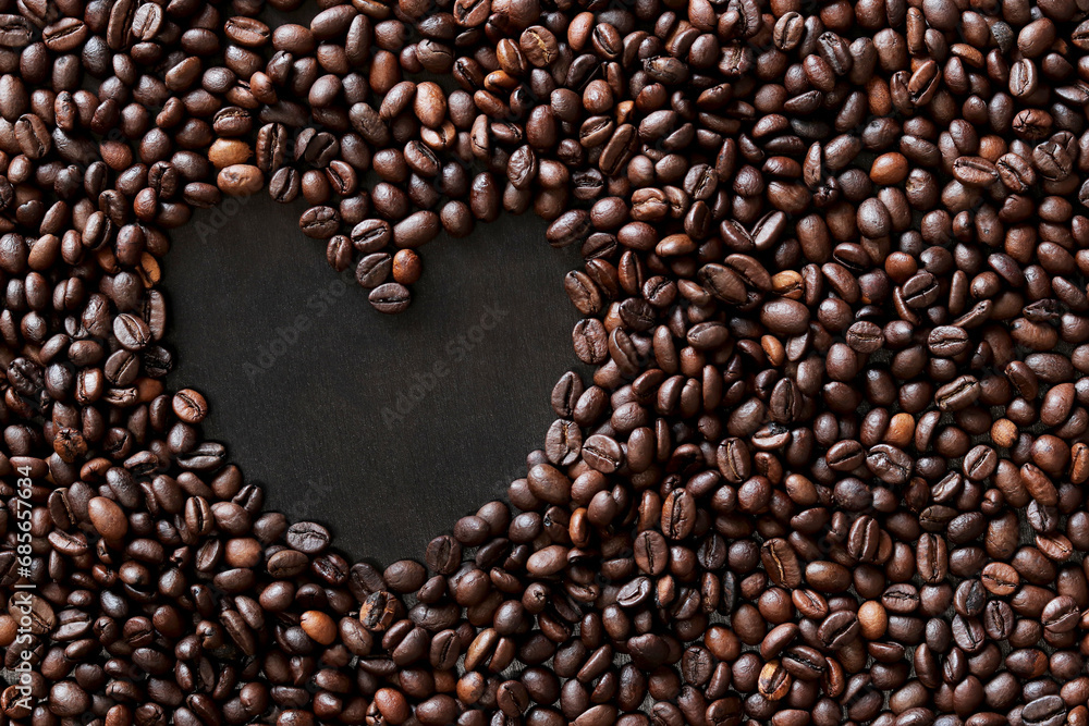 Coffee beans are laid out in the shape of a heart on a dark wooden surface. Top view. Roasted coffee beans, copy space Coffee beans are laid out in the shape of a heart on a dark wooden surface. Top view. Roasted coffee beans, copy space