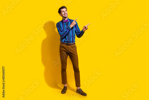 Full size photo of positive guy dressed shirt trousers look directing at proposition empty space isolated on yellow color background © deagreez