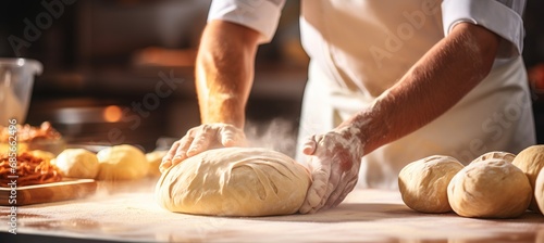 Skilled baker kneading dough in bakery for bread baking bright photo with blurred background photo