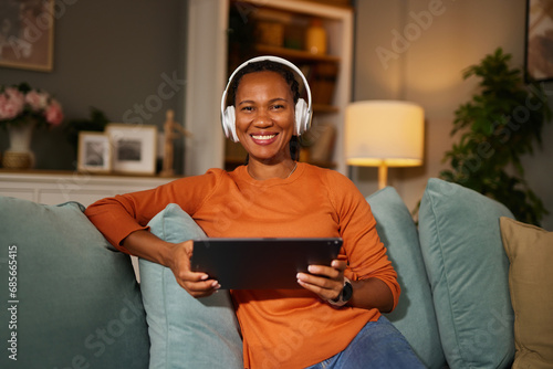 Woman relaxing while listening to music on digital tablet at home