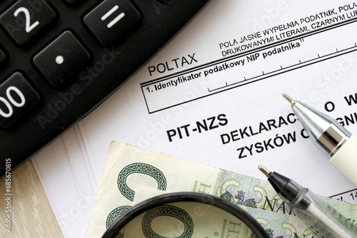 Declaration of income amount from unrealized profits obtained by enterprise as inheritance, PIT-NZS form on accountant table with pen and polish zloty money bills close up photo