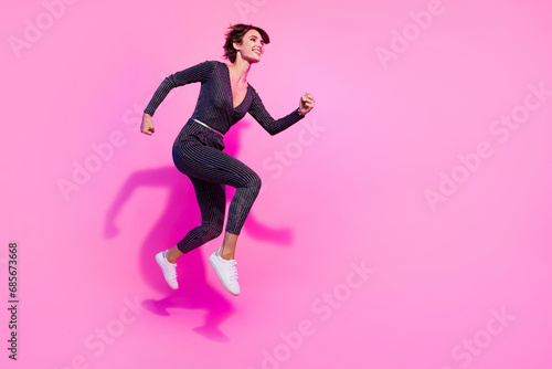 Full length photo of good mood charming girl dressed glamour overall running jumping high empty space isolated pink color background