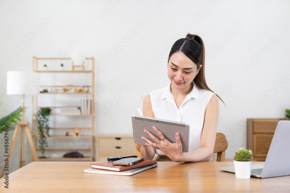 Asian woman working at home using tablet device Look at the internet, use social media, in video conferences with co-workers. Asian woman working at home using tablet device Look at the internet, use social media, in video conferences with co-workers.