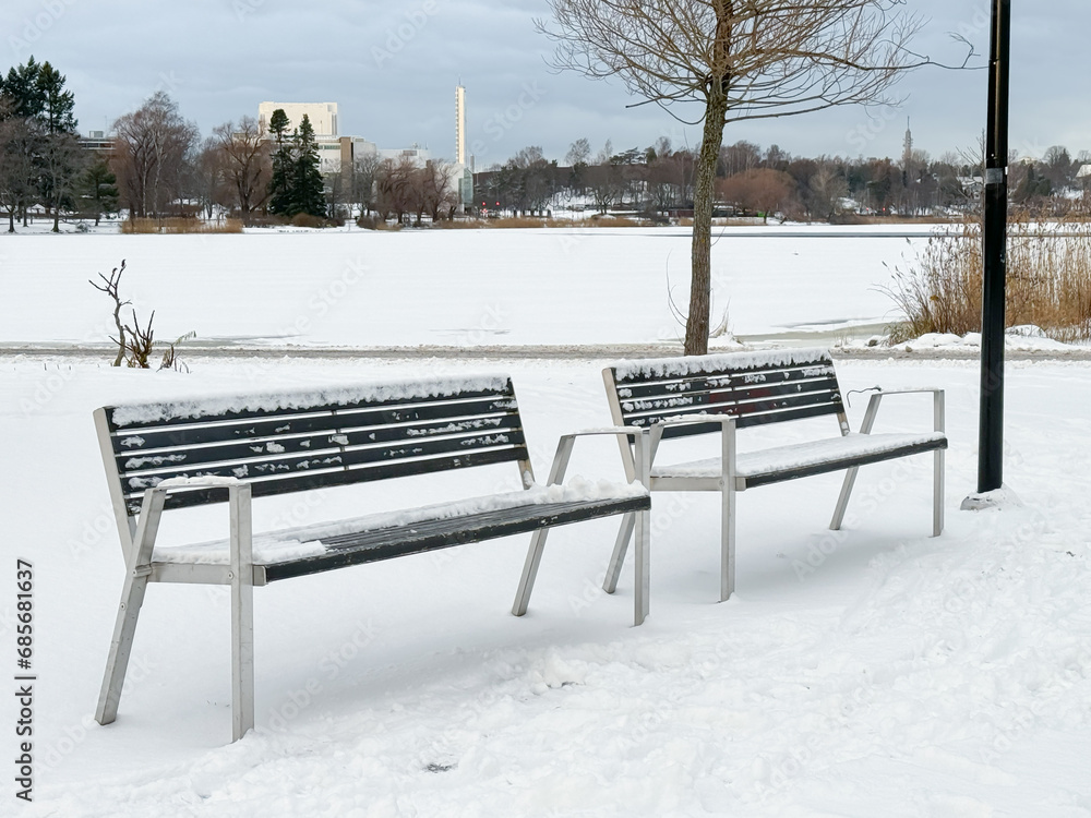 Bench covered in snow at the edge of a lake
