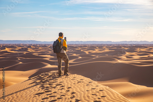 An adventurer stands on a dune, gazing at the endless horizon, embodying the spirit of exploration in the vast desert landscape.