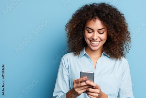 Portrait of a happy young african american woman using mobile phone on blue background