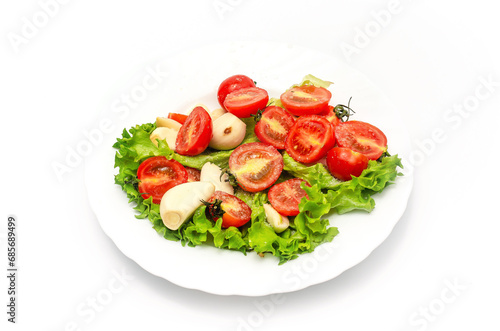 Delicious vegetable salad in a bowl on a white background. Chopped tomatoes, lettuce, garlic, salt.