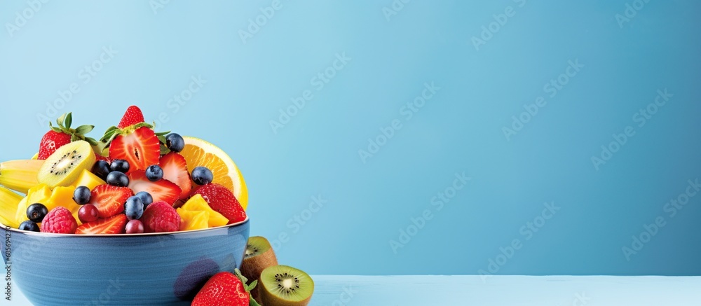 Tasty fruit salad in a blue bowl isolated copy space blue background