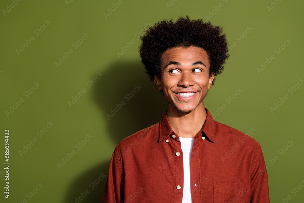 Portrait of pleasant funny guy with chevelure hairdo wear stylish shirt look at discount empty space isolated on green color background Portrait of pleasant funny guy with chevelure hairdo wear stylish shirt look at discount empty space isolated on green color background