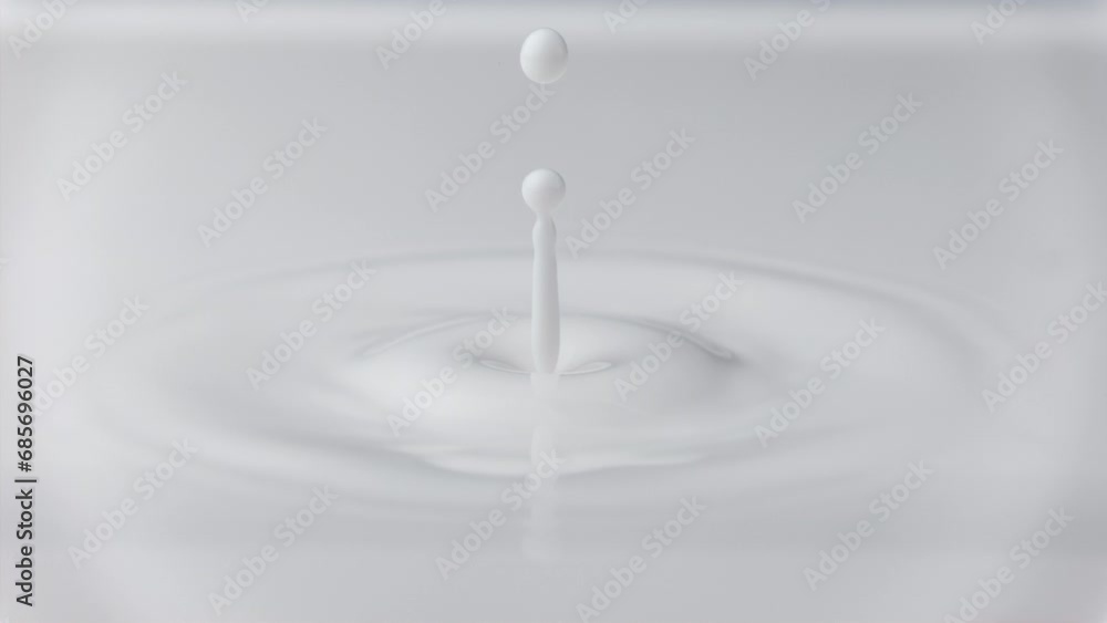 Fresh milk drop falling and splashing in a milky pool. Slow motion macro shot Fresh milk drop falling and splashing in a milky pool. Slow motion macro shot