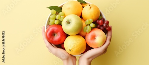 Female hands hold many assorted fruits of a healthy eating isolated yellow background