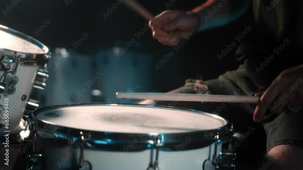 The drummer plays drums in a dark studio with lights on the back. The drummer plays drums in a dark studio with lights on the back.