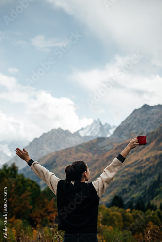 a girl with a mug in her hand stretches in the mountains