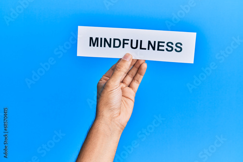 Hand of caucasian man holding paper with mindfulness word over isolated blue background © Krakenimages.com