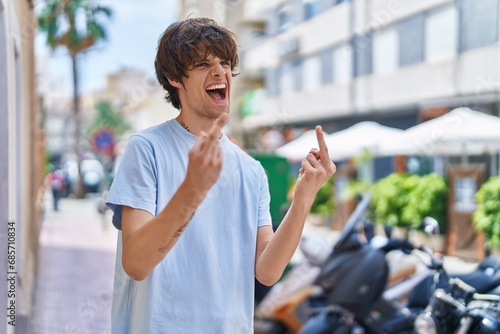 Young blond man doing bad gesture with fingers at street © Krakenimages.com