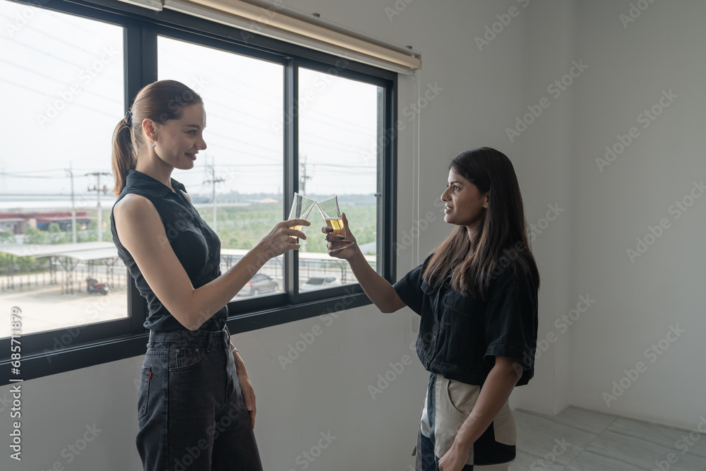 Obraz premium Two business beautiful young women are drinking and talking while standing near the window.