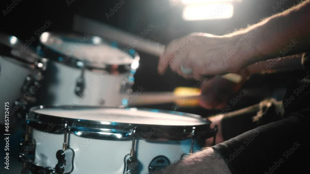 The drummer plays drums in a dark studio with lights on the back. The drummer plays drums in a dark studio with lights on the back.