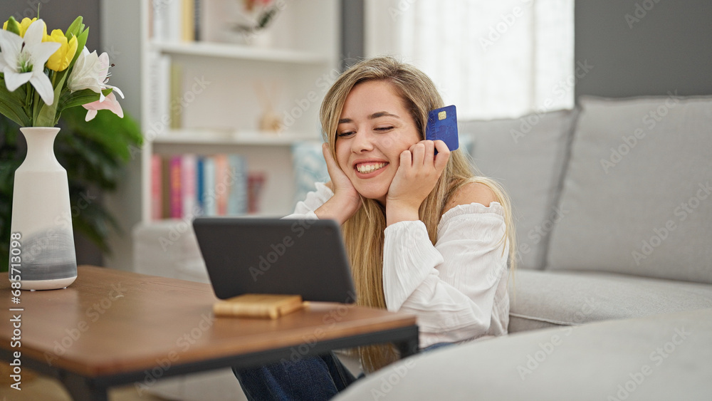Young blonde woman shopping with touchpad and credit card sitting on floor at home Young blonde woman shopping with touchpad and credit card sitting on floor at home