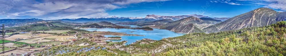 Drone panorama over the Mediano reservoir in the Spanish Pyrenees with snow-covered mountains in the background