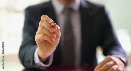 Businessman holding ballpoint pen in front of camera at work in office closeup. Signing contract for employment concept