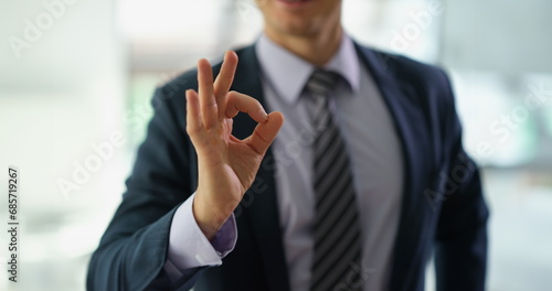 Businessman in suit showing hand gesture ok at work in office closeup. Approve good choice concept photo