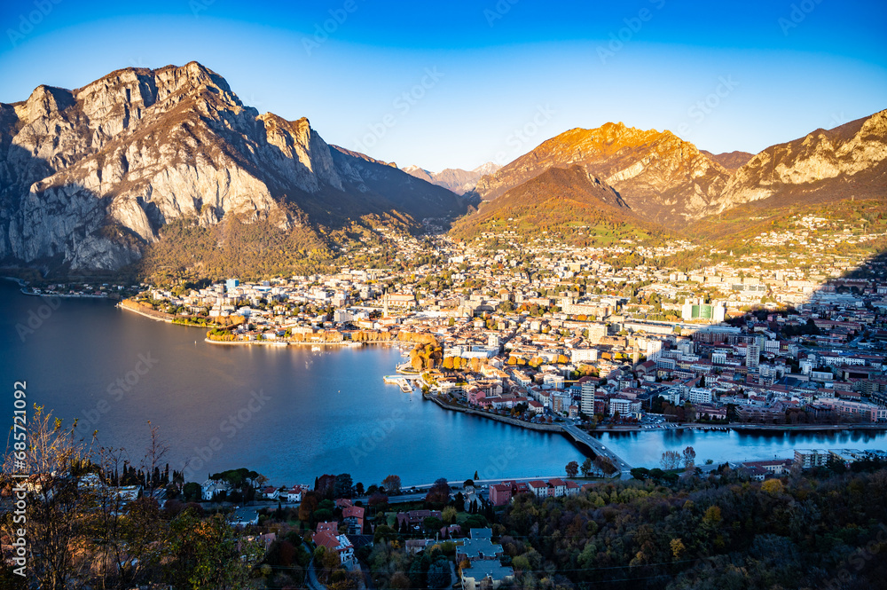 The city of lecco, shot from above, by day, with the surrounding mountains.
