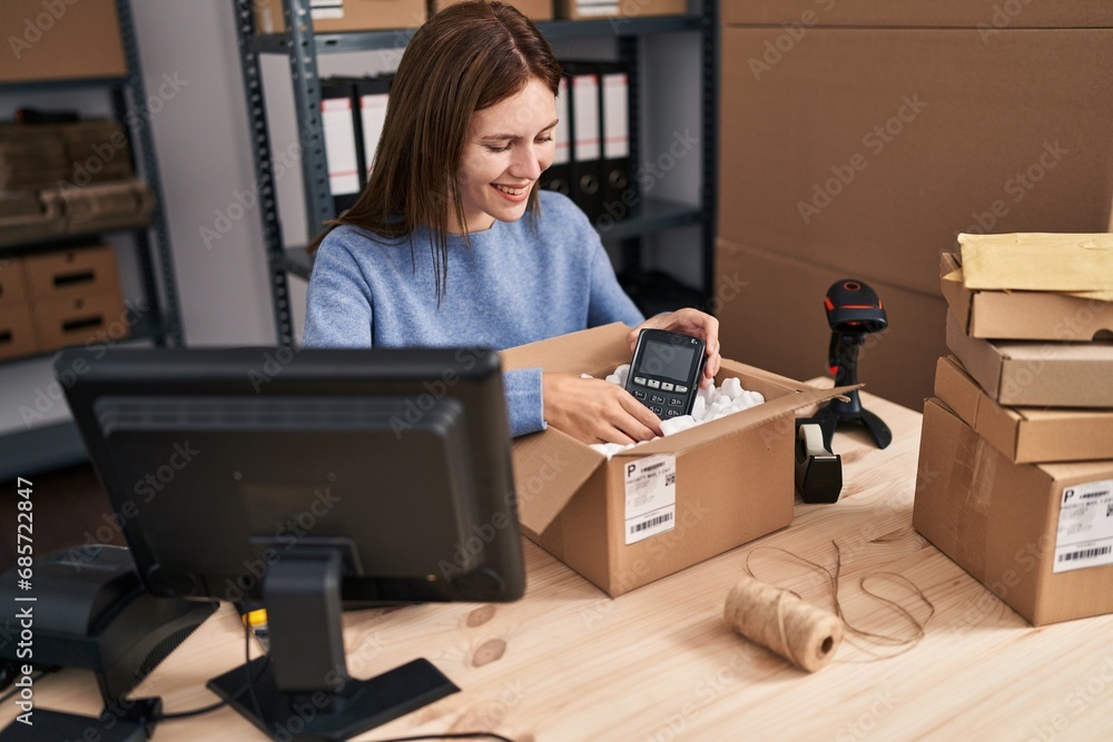 Young blonde woman ecommerce business worker packing data phone on cardboard box at office Young blonde woman ecommerce business worker packing data phone on cardboard box at office