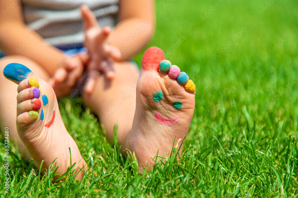 Naklejka premium Child feet drawing smile in the park on the grass. Selective focus.