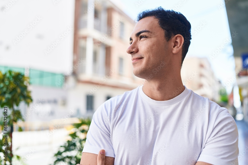 Fototapeta premium Young hispanic man standing with arms crossed gesture at street