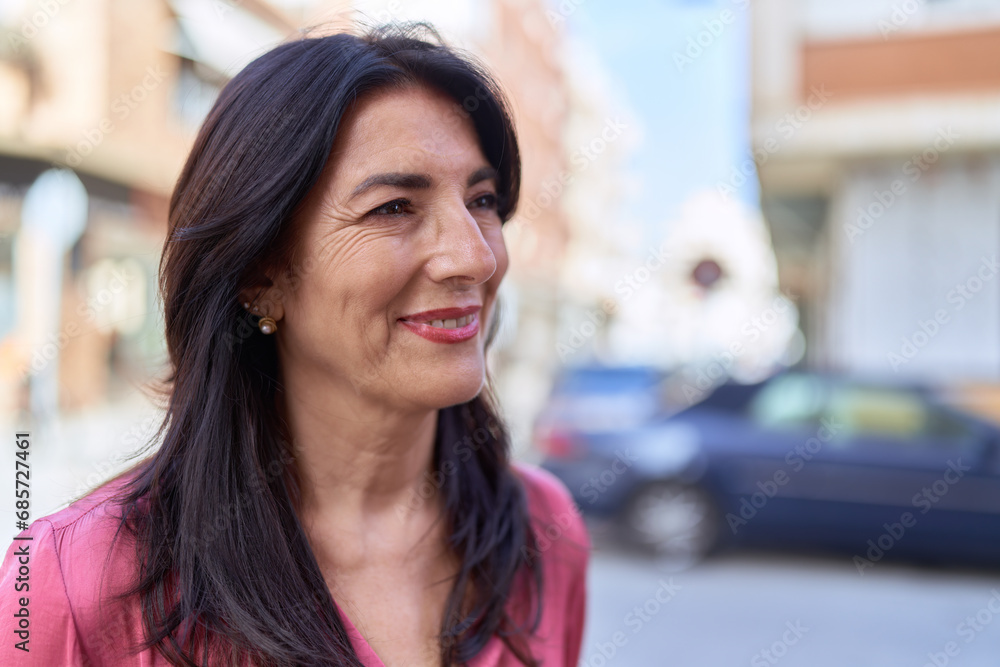 Middle age hispanic woman smiling confident looking to the side at street
