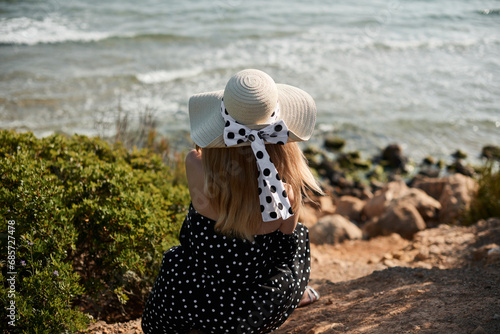 Girl in hat and polka dot dress on seashore. Salou, Costa Dorada in province of Tarragona. Spain.