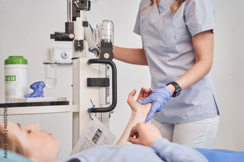 Cropped view of the woman doctor holding hand of lady patient while preparing for MRI Cropped view of the woman doctor holding hand of lady patient while preparing for MRI