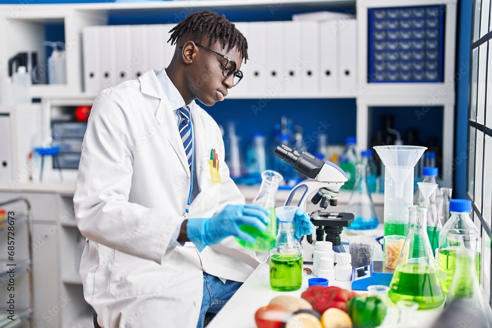 African american man scientist pouring liquid on test tube at laboratory African american man scientist pouring liquid on test tube at laboratory