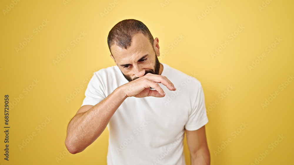 Young hispanic man coughing over isolated yellow background Young hispanic man coughing over isolated yellow background