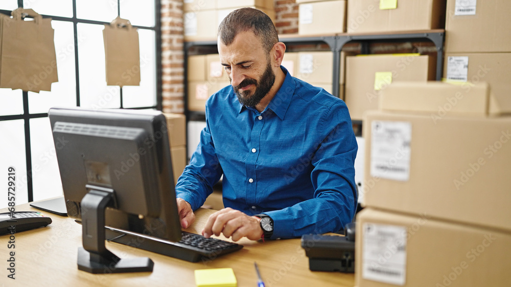 Young hispanic man ecommerce business worker using computer with serious face at office Young hispanic man ecommerce business worker using computer with serious face at office
