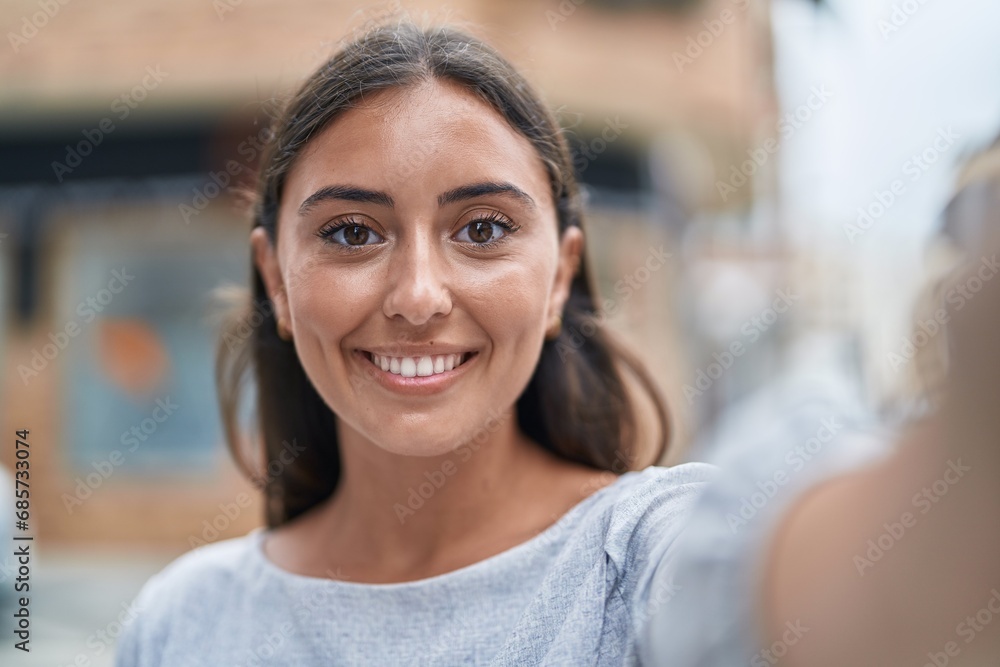 Young beautiful hispanic woman smiling confident making selfie by camera at street