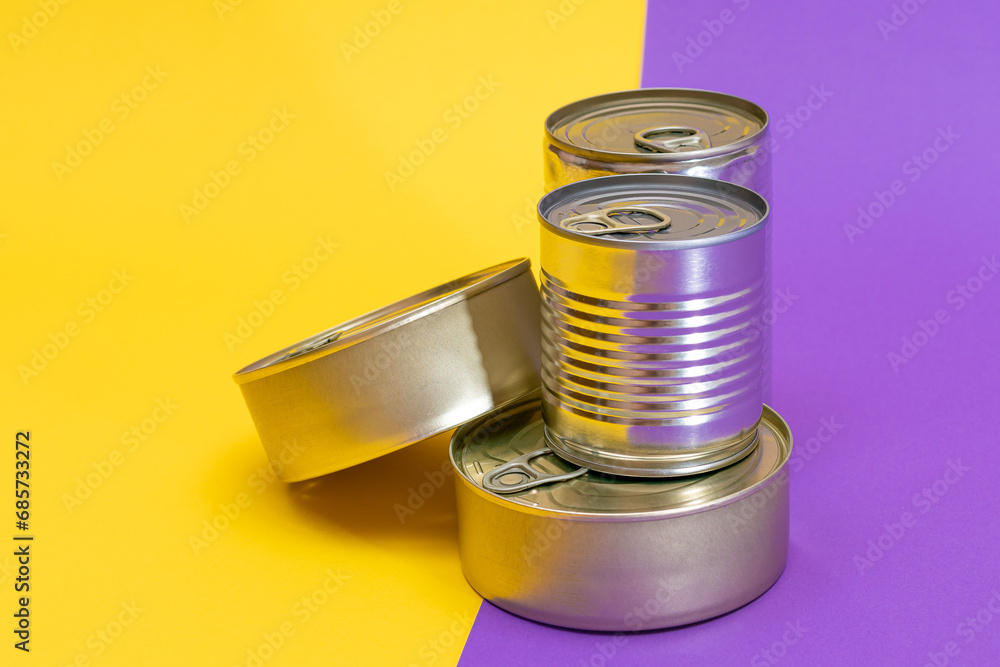A Group of Stacked Tin Cans with Blank Edges on Split Yellow and Violet Background. Canned Food. Different Aluminum Cans for Safe and Long Term Storage of Food. Steel Sealed Food Storage Containers A Group of Stacked Tin Cans with Blank Edges on Split Yellow and Violet Background. Canned Food. Different Aluminum Cans for Safe and Long Term Storage of Food. Steel Sealed Food Storage Containers