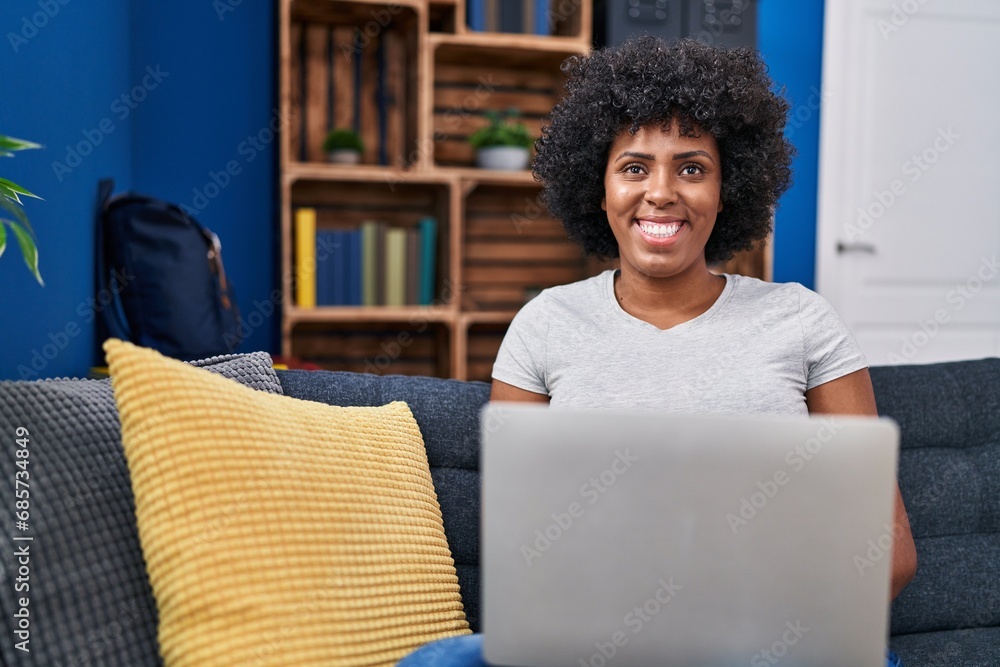 African american woman using laptop sitting on sofa at home African american woman using laptop sitting on sofa at home