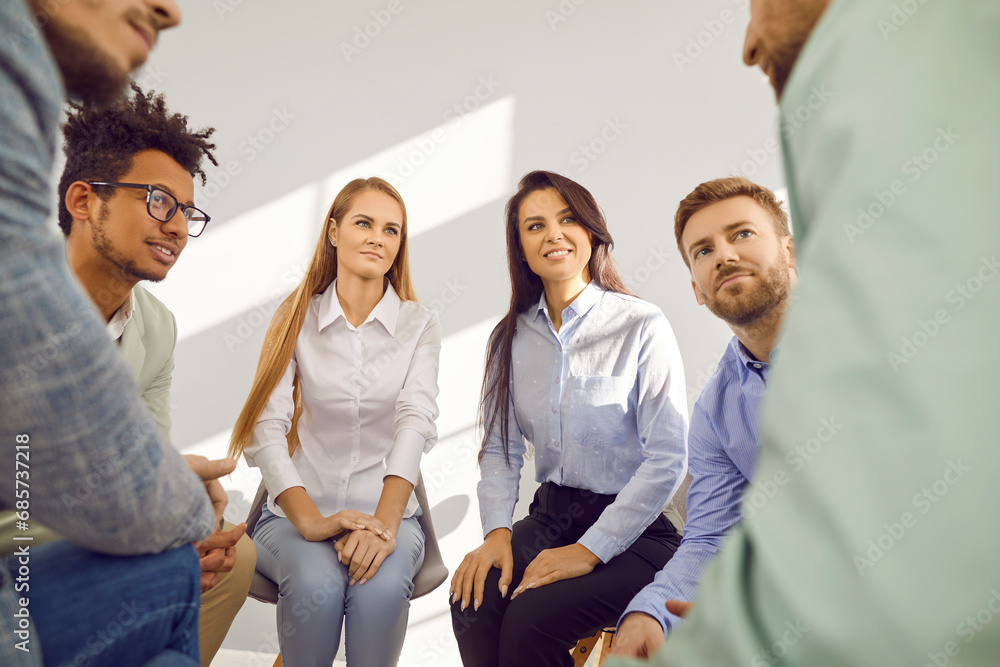 Close up photo of a group of business people sitting on chairs in circle and talking on meeting. Company employees making great decisions with brainstorming. Cowokers listen to their colleague. Close up photo of a group of business people sitting on chairs in circle and talking on meeting. Company employees making great decisions with brainstorming. Cowokers listen to their colleague.