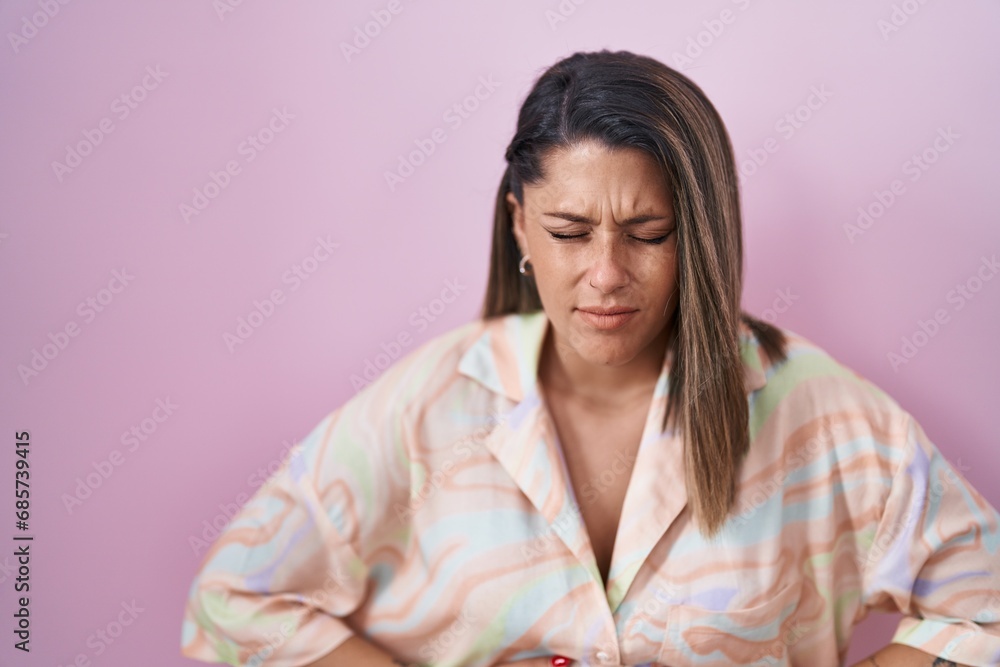 Blonde woman standing over pink background with hand on stomach because indigestion, painful illness feeling unwell. ache concept. Blonde woman standing over pink background with hand on stomach because indigestion, painful illness feeling unwell. ache concept.