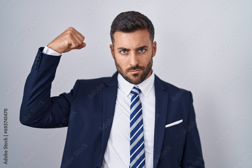 Handsome hispanic man wearing suit and tie strong person showing arm muscle, confident and proud of power Handsome hispanic man wearing suit and tie strong person showing arm muscle, confident and proud of power