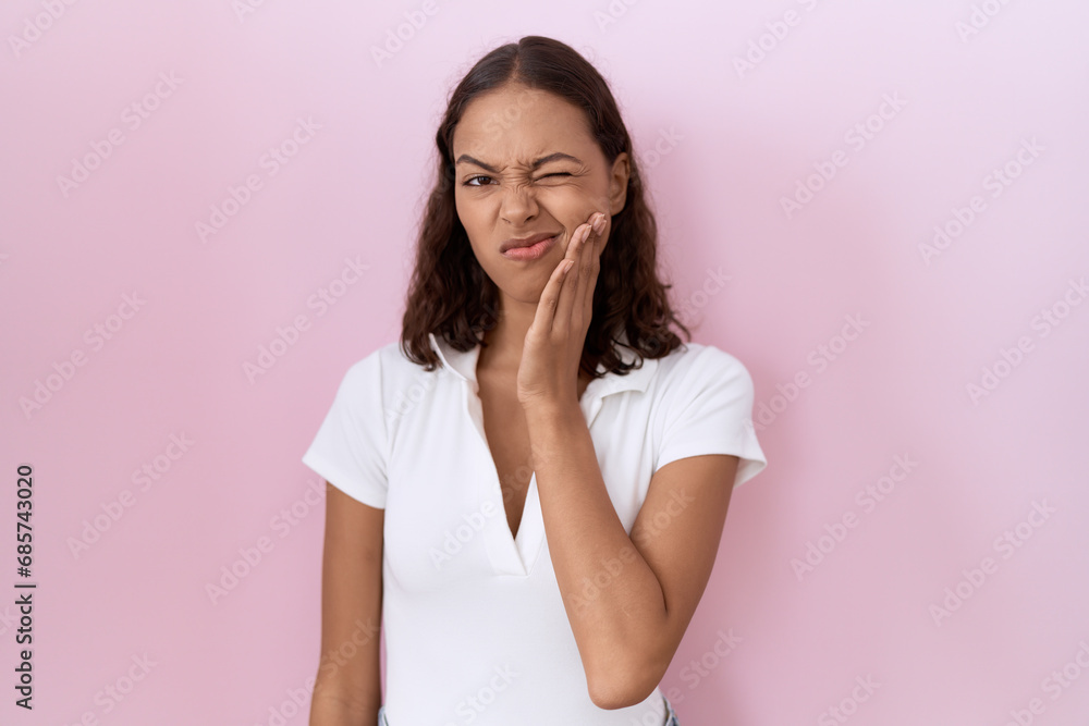 Young hispanic woman wearing casual white t shirt touching mouth with hand with painful expression because of toothache or dental illness on teeth. dentist Young hispanic woman wearing casual white t shirt touching mouth with hand with painful expression because of toothache or dental illness on teeth. dentist