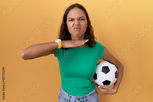 Young hispanic woman holding ball cutting throat with hand as knife, threaten aggression with furious violence © Krakenimages.com